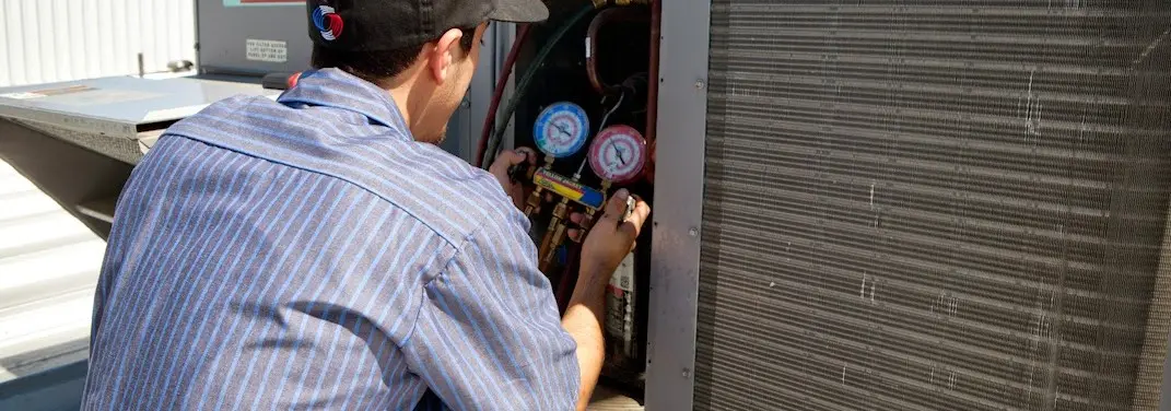 HVAC technician servicing a condenser unit in Poplar Bluff